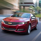 A red Chevrolet impala sedan driving on a street.